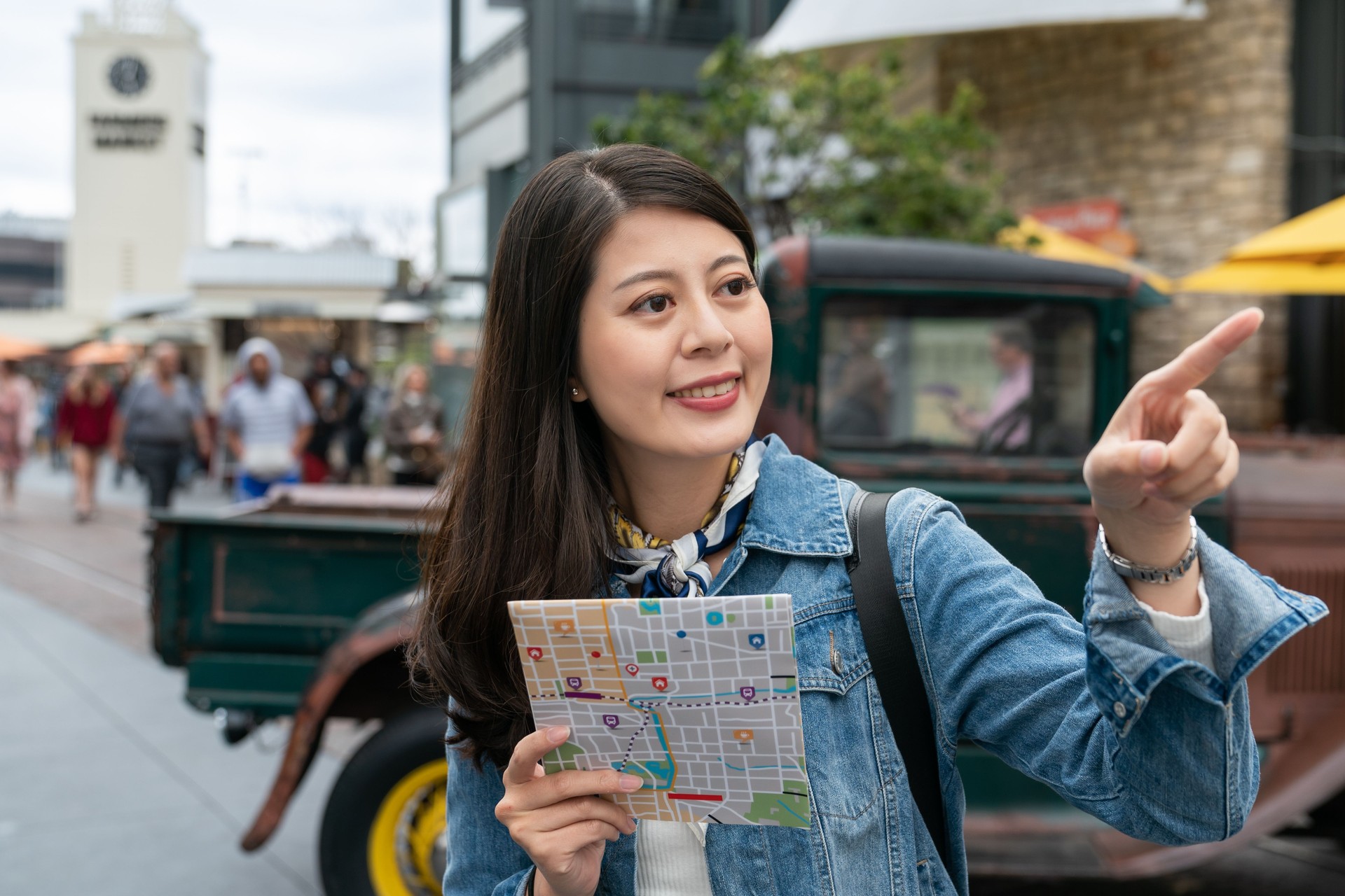 smile asian young backpacker woman using map for sightseeing outdoor Farmers Market in Los Angeles, USA during vacation.